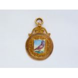 A late Victorian 9ct gold fob having a shield-shaped plaque hand-enamelled in depiction of a pigeon,