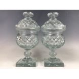 A pair of George IV cut glass sweetmeat urns with covers, having hobnail, diamond and fan cut