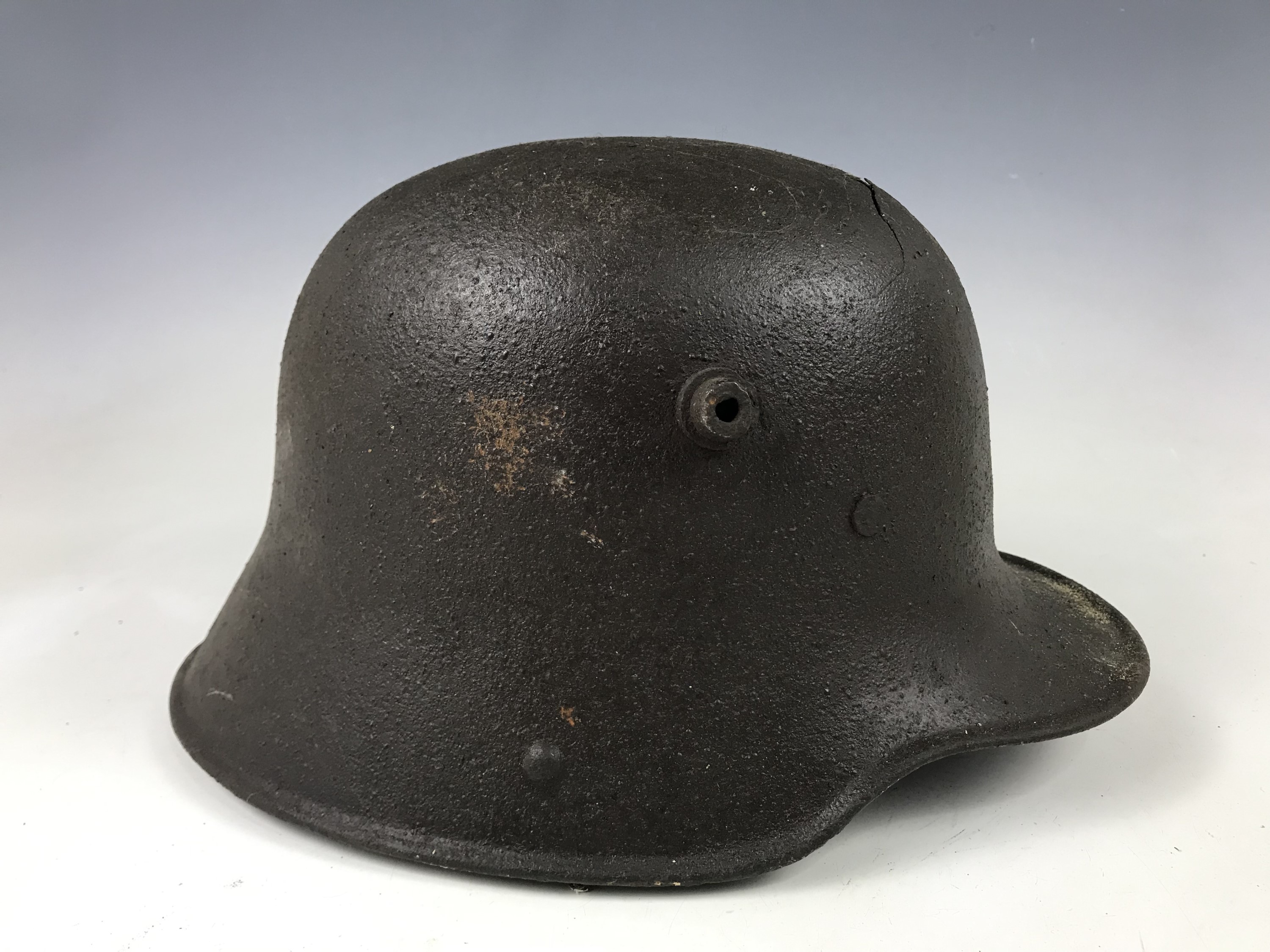 A relic Imperial German steel helmet exhibiting fractures