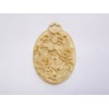A 1920s carved ivory pendant, of oval shape, having bas-relief roses and foliage, 4 x 5 cm