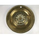 A 16th Century Nuremberg brass alms dish, having a shallow petal swirled boss reserved within a band