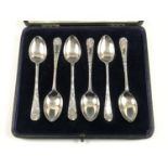 A cased set of six Edwardian silver coffee spoons, having moulded foliate C-scrolls to the stems,