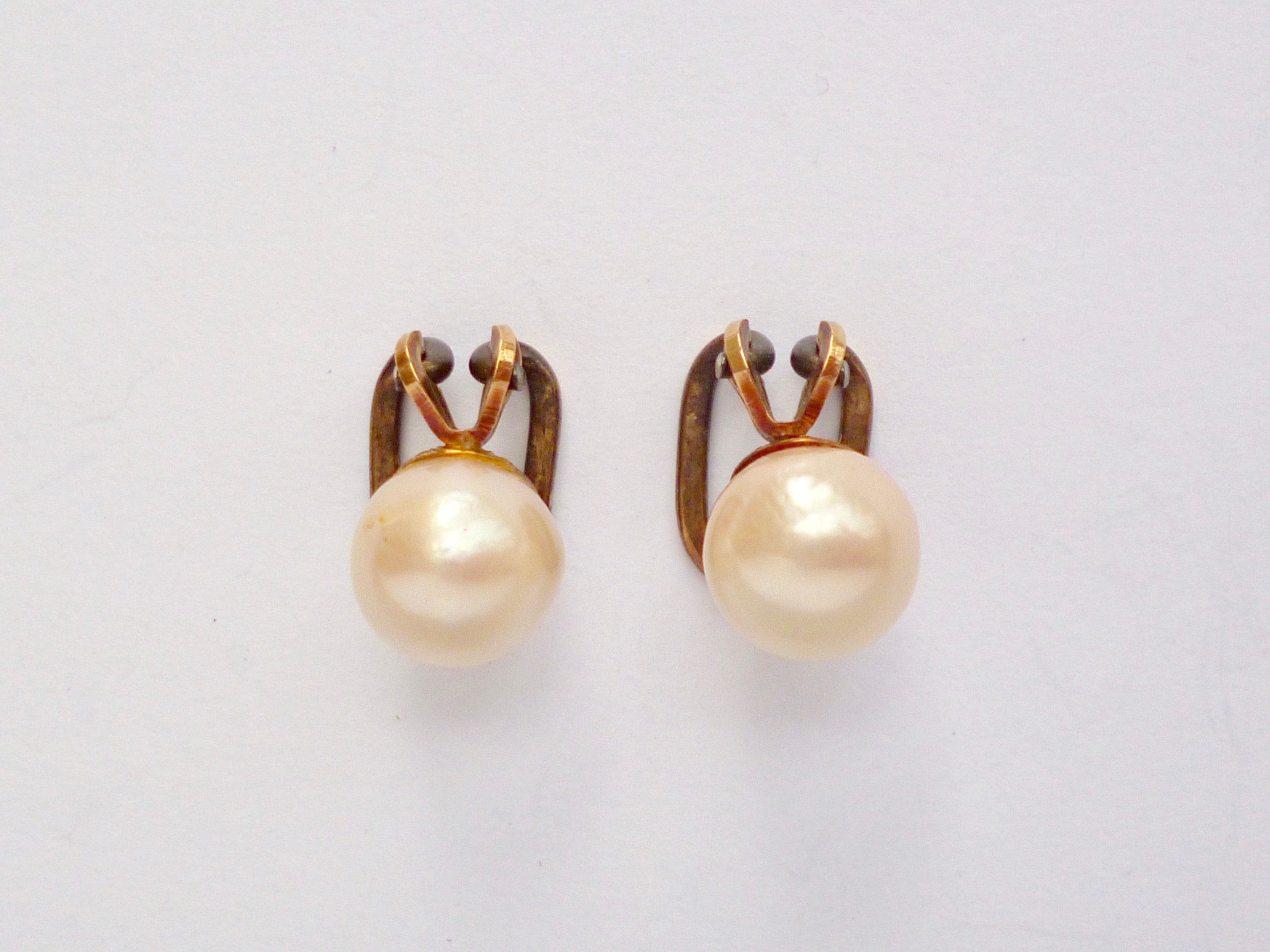 A pair of yellow-metal and pearl ear clips, pearls each approximately 8.5 mm, tests as gold