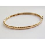 A slender 9ct gold hinged bangle, having bright-cut feather edging, 4.4g total