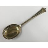 A George V silver-gilt berry / dredging spoon, having a shaped stem reticulated and engraved with