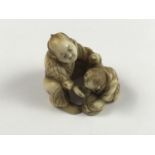 A Meiji Japanese carved ivory netsuke modelled as a crouching man giving assistance to a weary