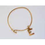 A vintage 9ct gold bangle with 9ct gold Gucci charm in the form of the letter 'E', 10.2g
