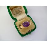 A vintage 9ct gold and amethyst dress ring, the oval-cut stone being claw set and flanked by cleft