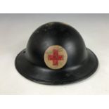 A Second World War Civil Defense helmet shell bearing a red cross device