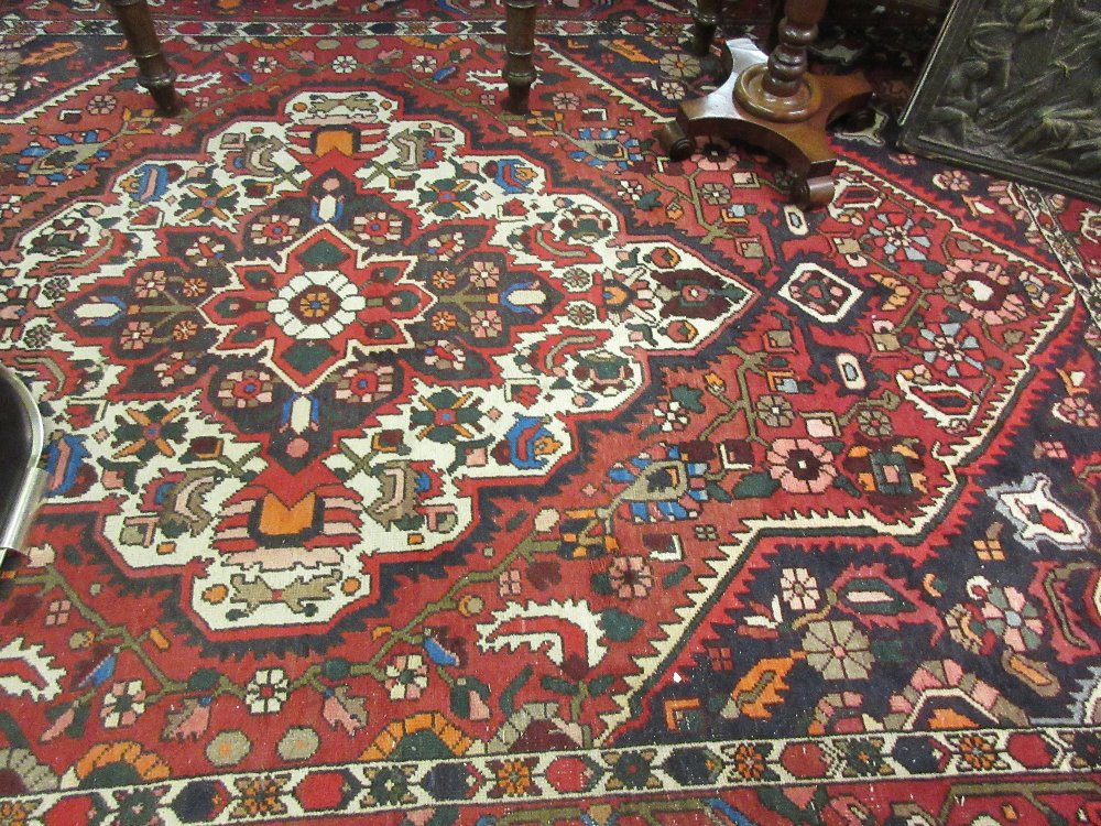 20th Century Kurdish carpet with a medallion and all-over stylised floral design on a red ground