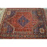 Shiraz rug with a medallion and all-over stylised floral design on a red ground with corner designs