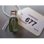 Miniature pale green and clear glass perfume bottle with an ornate white metal top and stopper,