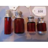 Group of four various ruby glass perfume bottles with white metal mounts, ranging in height from 4.