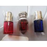 Two miniature cranberry / red glass perfume bottles with white metal mounts and a similar blue