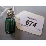 Miniature green faceted glass perfume bottle with ornate white metal screw top and attached rings,