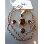 Yellow metal garnet and seed pearl pendant on a gold plated chain