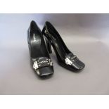 Pair of ladies Prada black patent leather court shoes with white metal buckle to the front bearing