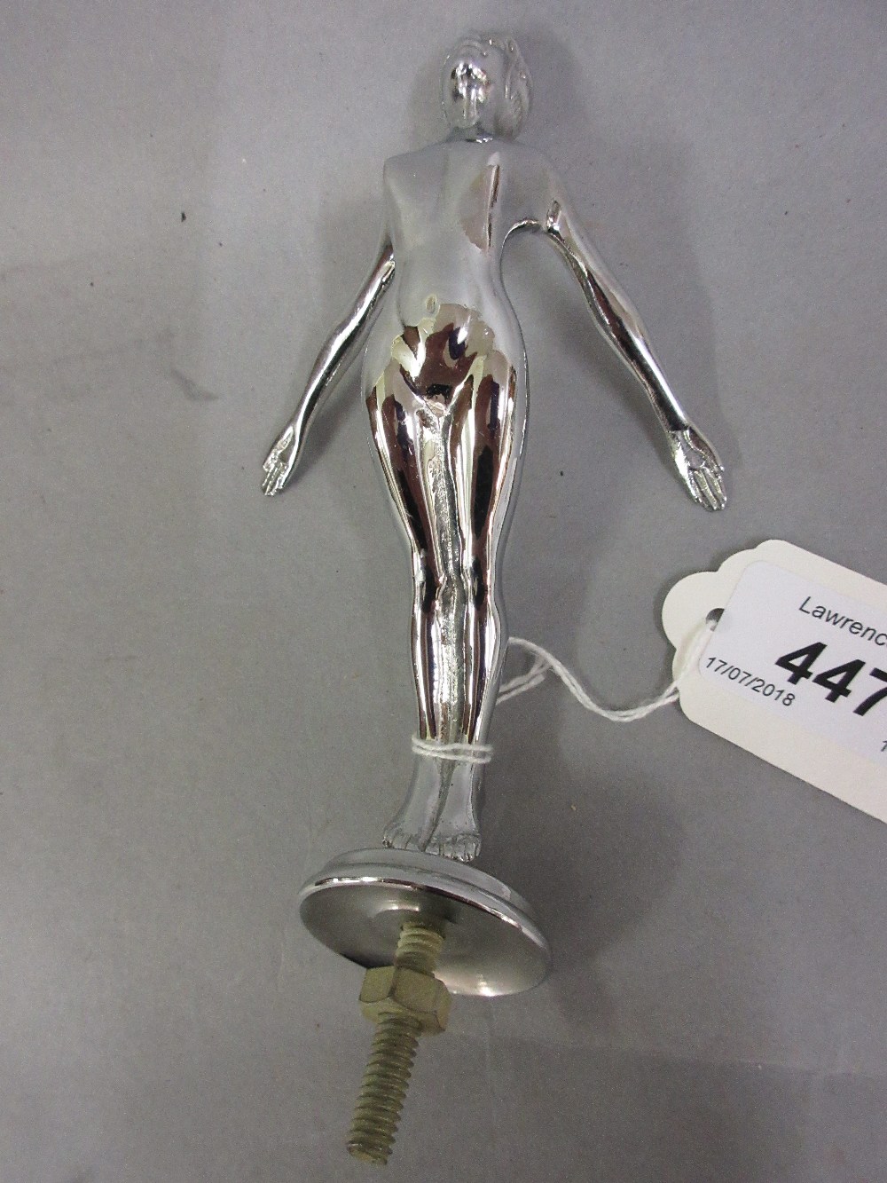Chrome plated car mascot in the form of a nude female with outstretched arms,