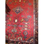 Kurdish rug with medallion and all-over stylised floral design on a red ground with borders,