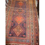 Kurdish rug with four central hooked medallions and multiple borders on a blue and rust ground (at