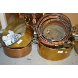 Graduated set of three copper iron handled cooking pots and three oval brass cooking pots with a