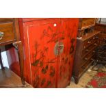 20th Century Oriental red lacquered two door side cabinet painted with figures and buildings in a
