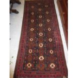 Afghan Belouch runner of all-over floral design with multiple borders on a burgundy ground,