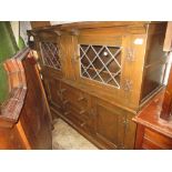 Reproduction oak court cupboard with two leaded doors above drawers and doors