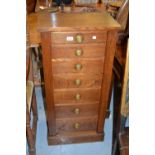 Oak Wellington chest of seven graduated drawers with circular brass handles on a plinth base
