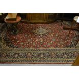 Kashan carpet with a lobed medallion and all-over floral design on a red ground with borders,