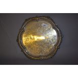 London silver salver with shaped rim and all-over engraved decoration on ball feet