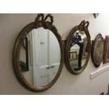 Pair of oval gilt framed wall mirrors with bow surmounts