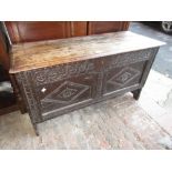 Small 17th Century oak coffer with a moulded plank lid above a carved two panel front on slab ends