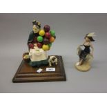 Figure of an old lady balloon seller and a figure of a bulldog mounted on a wooden plinth,