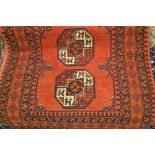 Afghan rug with typical repeating gol design on a rust ground