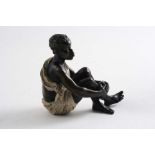 AN EARLY 20TH CENTURY COLD-PAINTED BRONZE of a young African man sitting cross-legged, wearing a