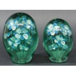 TWO GREEN GLASS DUMPS, of typical form, both with a spray of silver and blue petalled flowers,