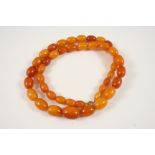 A SINGLE ROW AMBER BEAD NECKLACE 63cm. long, 45 grams.