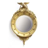 REGENCY STYLE CONVEX MIRROR, the circular plate with oval facetting beneath a gilt spread eagle