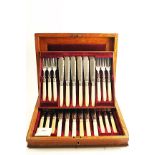 AN EDWARDIAN CASED SET OF TWELVE PAIRS OF IVORY HANDLED FISH KNIVES & FORKS with border engraving on