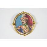 AN INDIAN PORTRAIT MINIATURE BROOCH depicting a regal gentleman, in a gold frame with half ball gold
