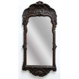 CONTINENTAL OAK WALL MIRROR, probably French, the shaped rectangular plate beneath a scrolling