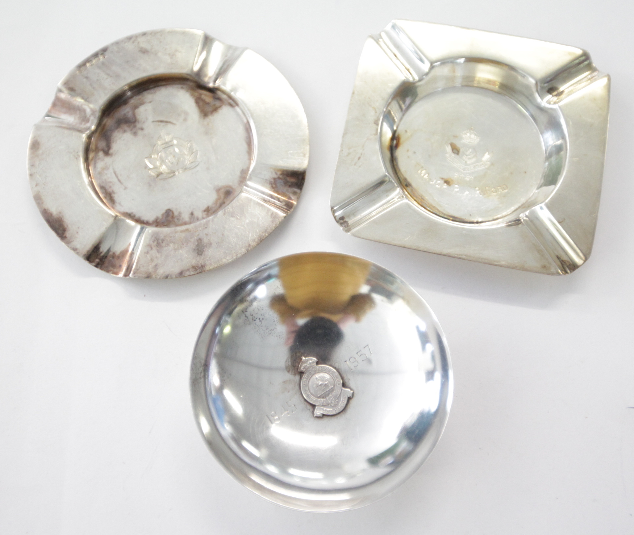 THREE SILVER ASHTRAYS. Including 1. A Royal Navy circular ashtray, with Kings Crown and Anchor