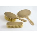 GOLD:- A 9 ct. three piece dressing table set of two brushes & hand mirror with engine turned