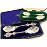 A CASED PAIR OF DECORATIVE FRUIT SERVING SPOONS with ship terminals and fluted bowls, by T. Bradbury