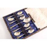 A CASED SET OF SIX HANDMADE TEA SPOONS and a matching sugar spoon with openwork basket of flower