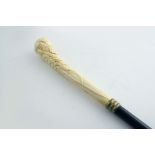 AN EARLY 20TH CENTURY WALKING CANE with a dark hardwood shaft & a brass ferrule, the handle carved