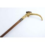 AN EARLY 20TH CENTURY WALKING STICK with an antler handle, carved with a grotesque long nosed