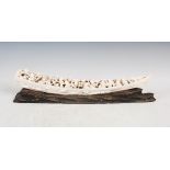 A Japanese ivory tusk carving, Meiji Period, carved as a long boat with figures and children, signed