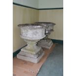 A pair of composite stone octagonal shaped garden urns, decorated with quatrefoil panels, raised